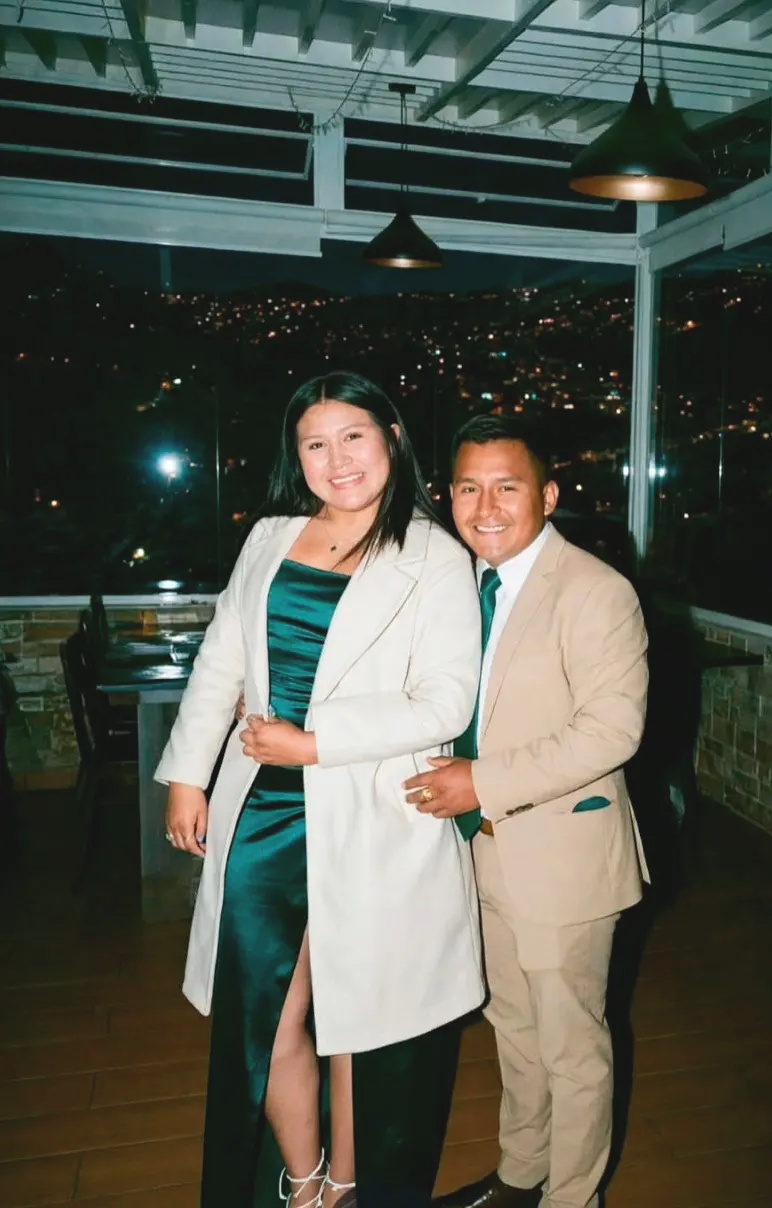 Ayato y Fabiola juntos, de noche, con la ciudad detrás